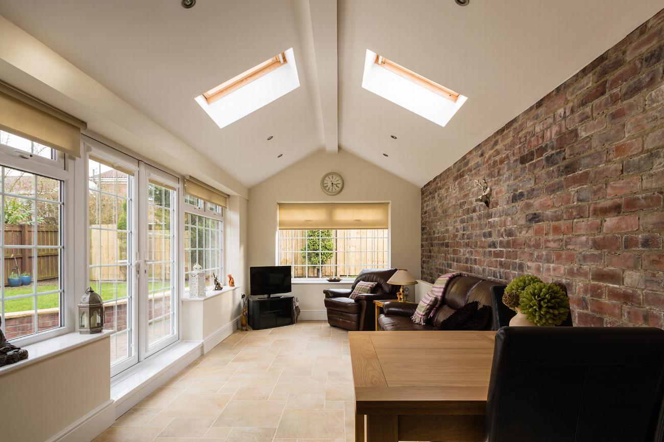 Bright single storey extension with roof windows and exposed brick wall